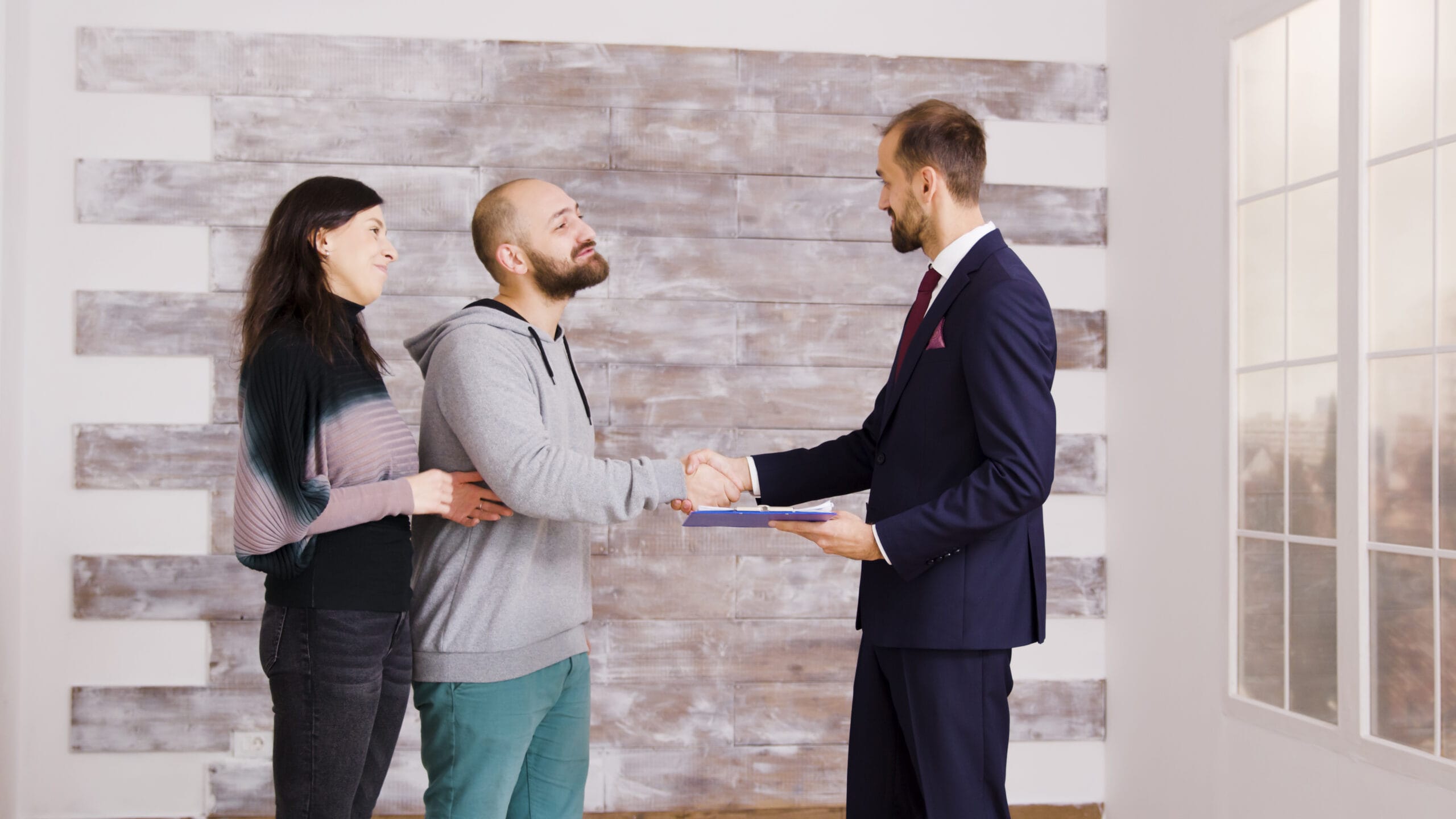 Realtor shaking hands with happy homebuyers after closing a successful real estate deal using AI-driven real estate comps and analysis.