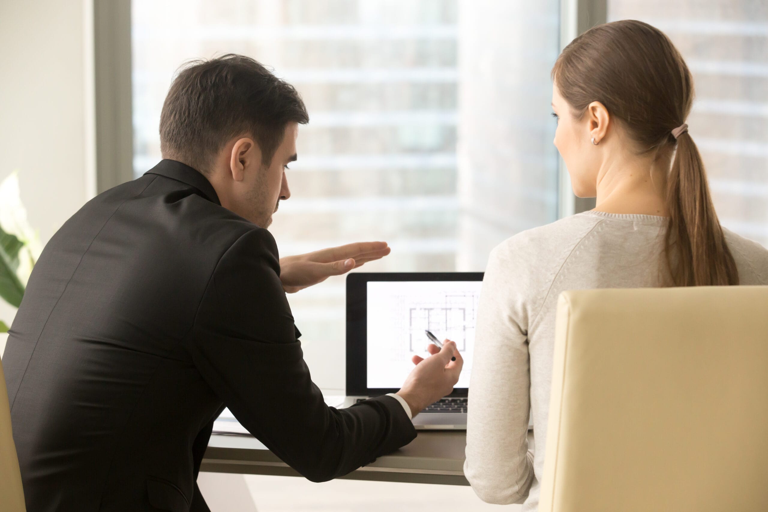 Real estate investor analyzing property data on a laptop with an agent.