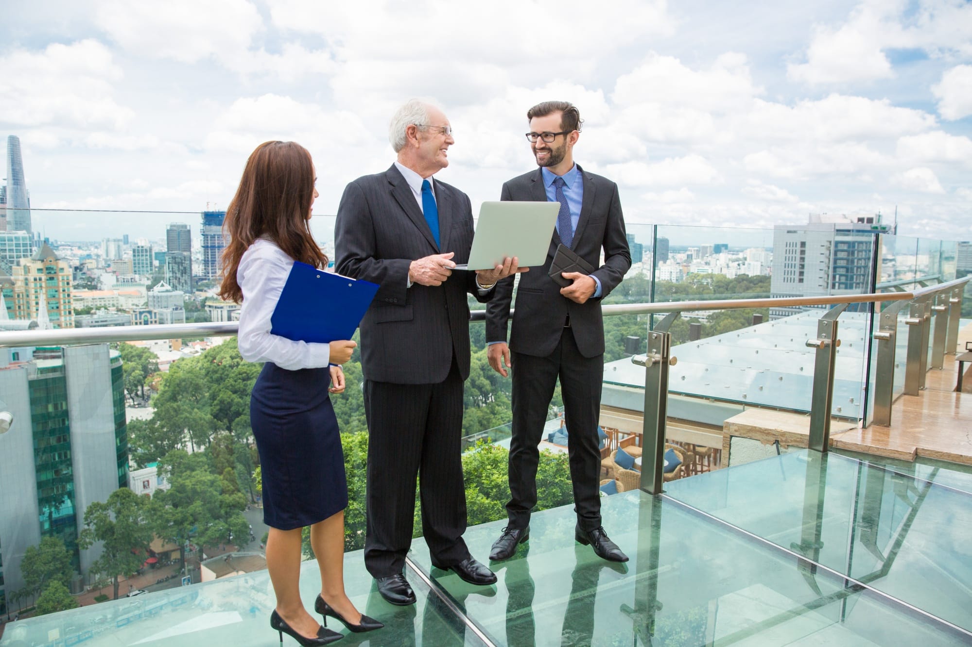 Group of real estate professionals shaking hands over closed deal, background shows data visualizations.