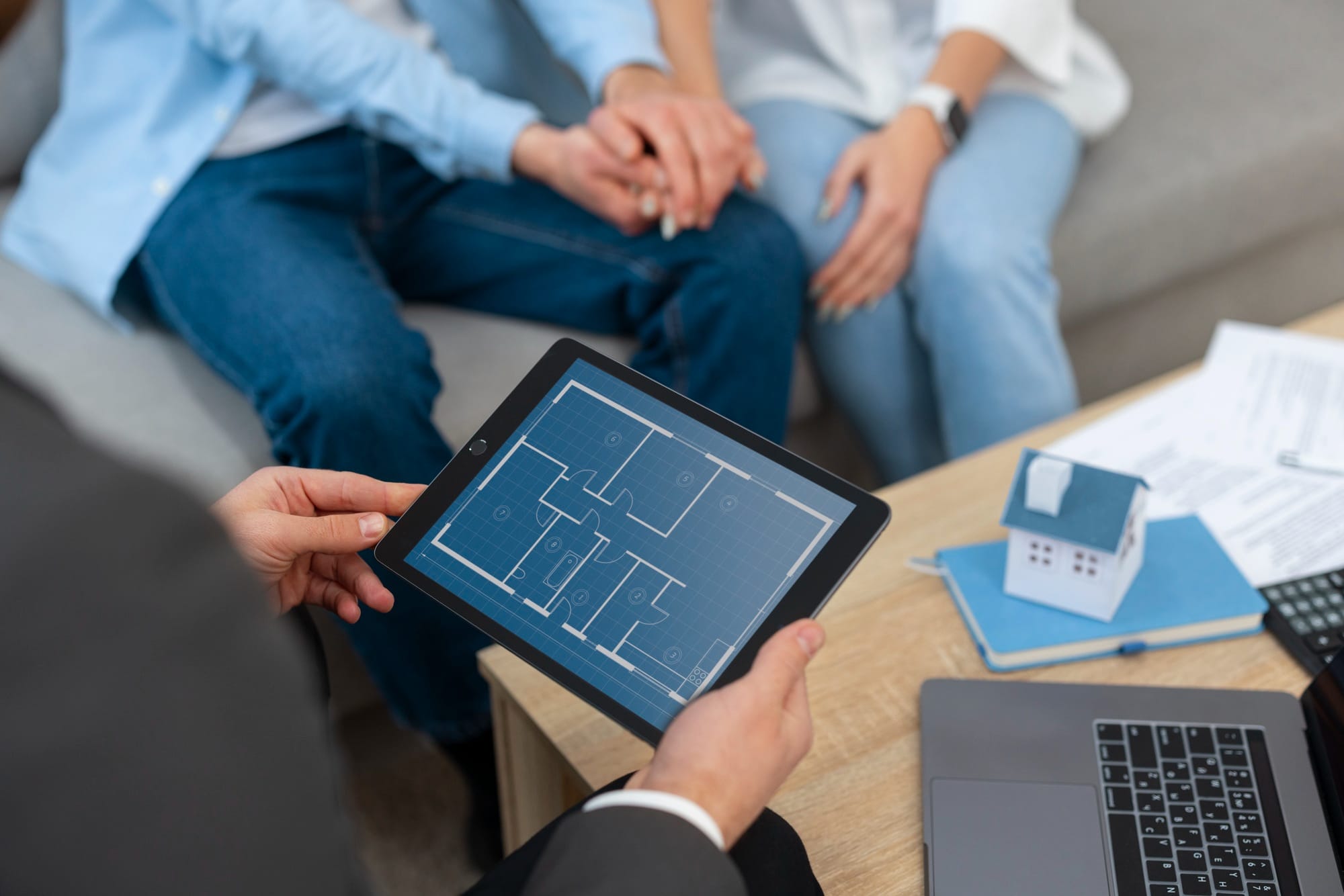 A professional presents a digital floor plan to a couple during a meeting about a new home or property investment.