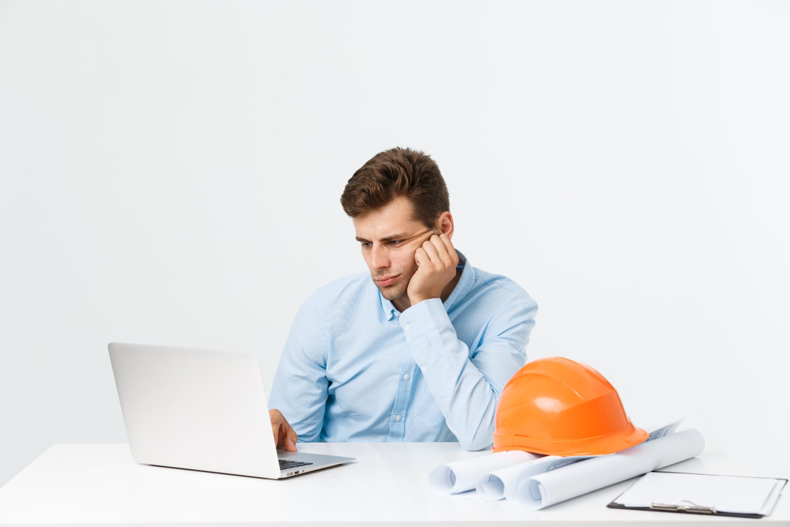 Frustrated real estate investor struggling with renovation cost estimation on a laptop with blueprints.