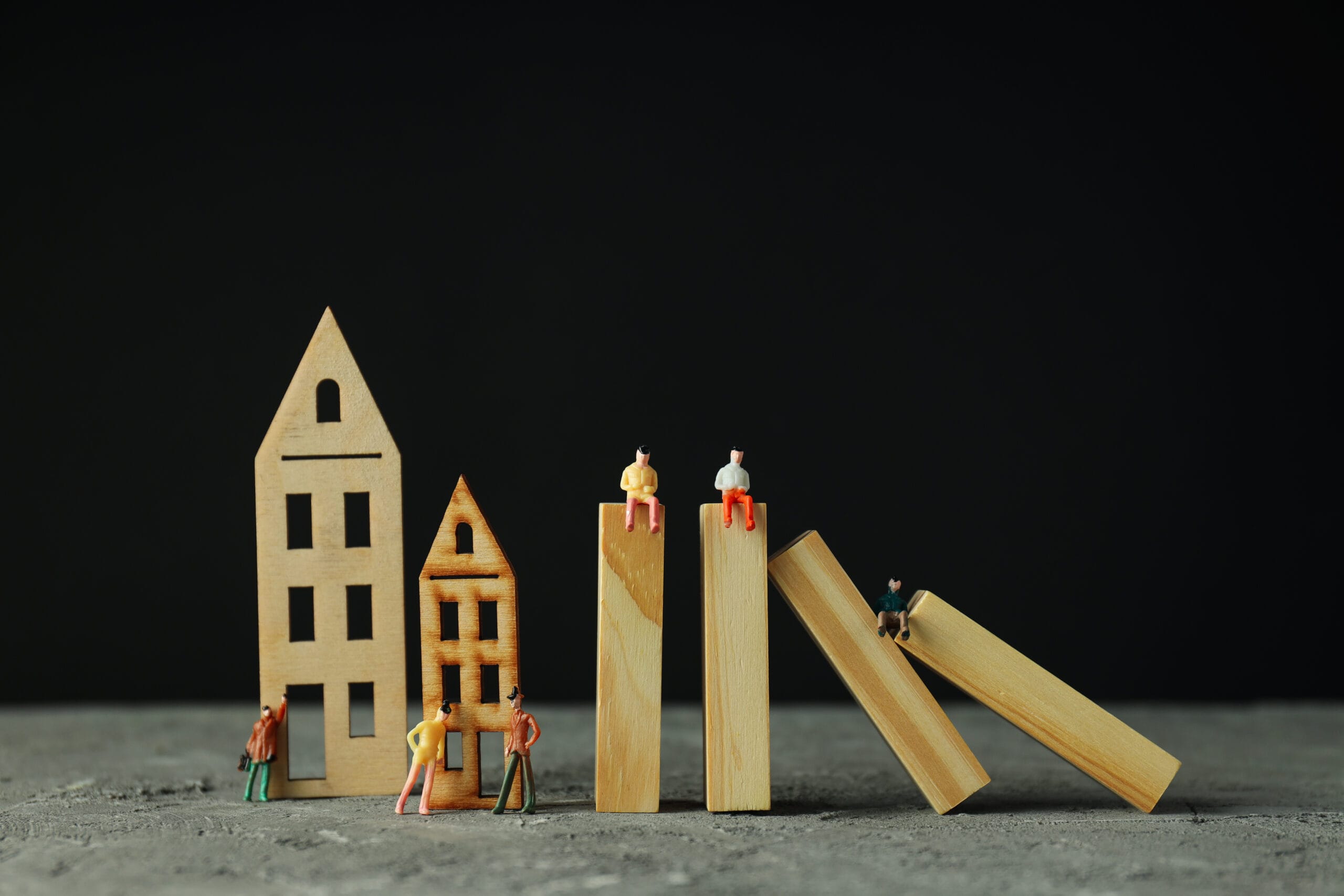Real estate risk and protection illustrated by falling houses and miniature people, symbolizing investment pitfalls and risk management