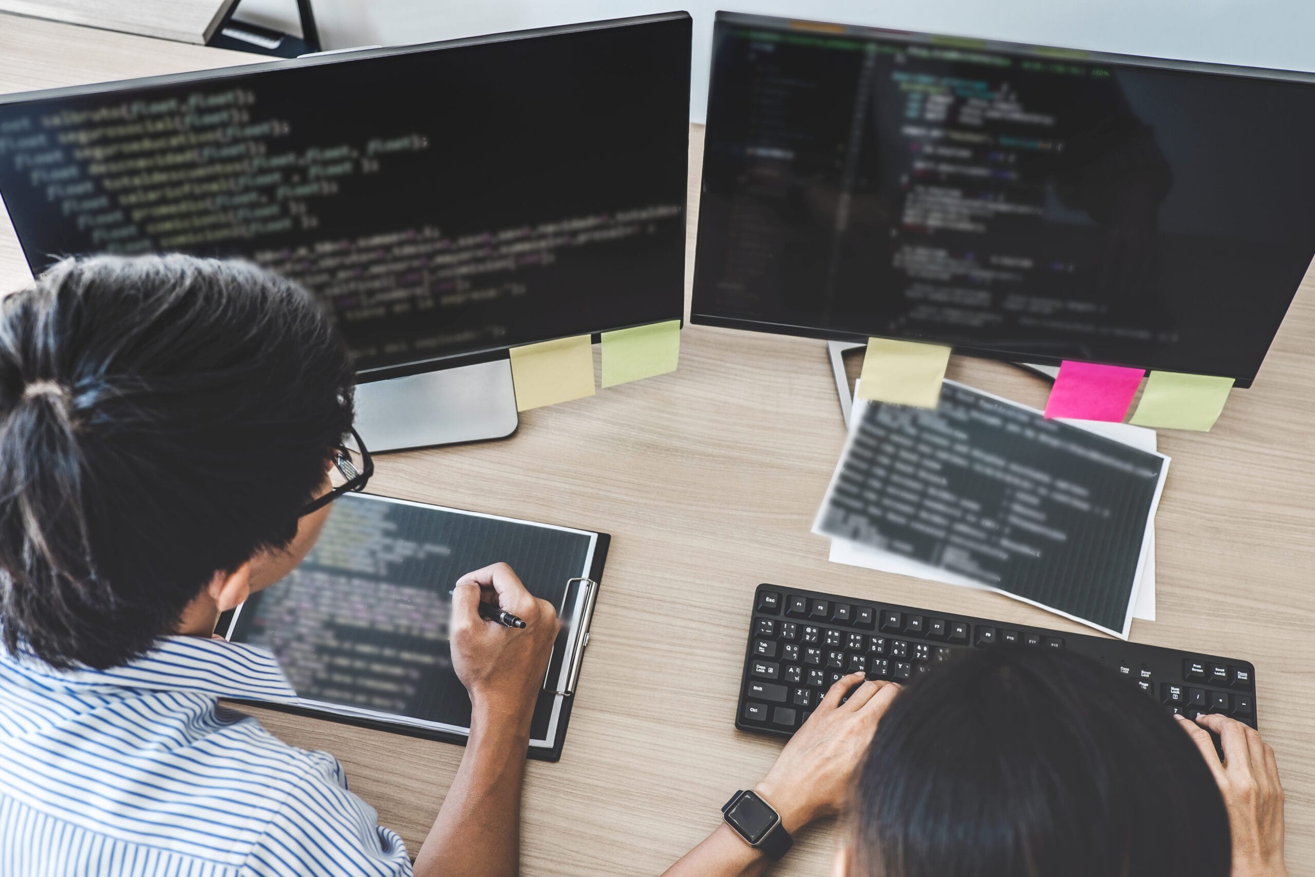 IT Developer working on dual monitors coding real estate API integration to use real estate data for property technology applications