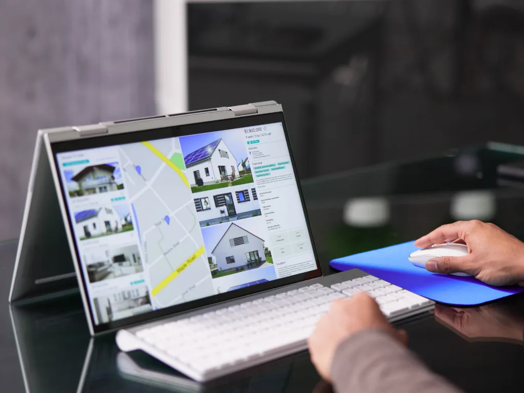 Real estate investor using a modern laptop to analyze property listings and digital maps with AI-powered real estate software