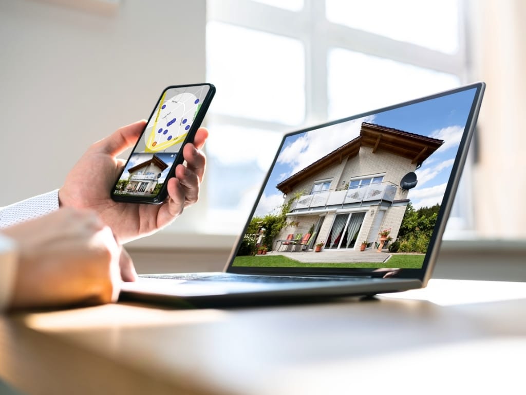 7 Best Investment Properties APIs for IT Developers in 2026 6 User viewing property listings on laptop and smartphone using AI-powered real estate application.
