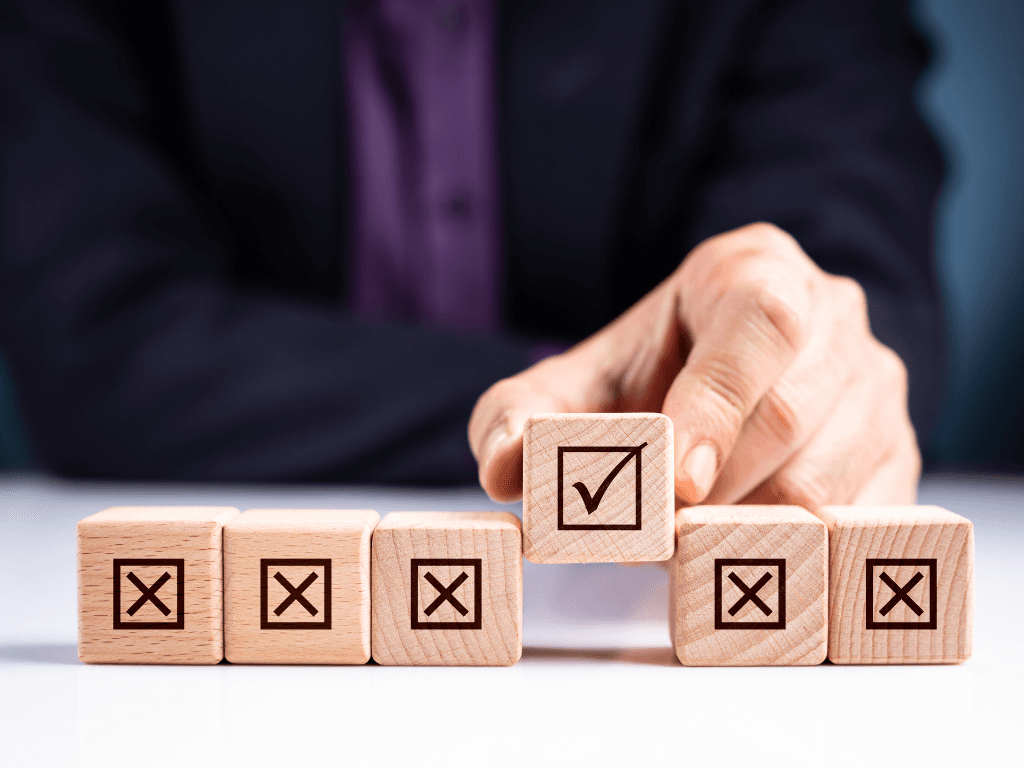 Businessperson selecting a wooden block with a check mark to represent choosing the best home value monitoring API
