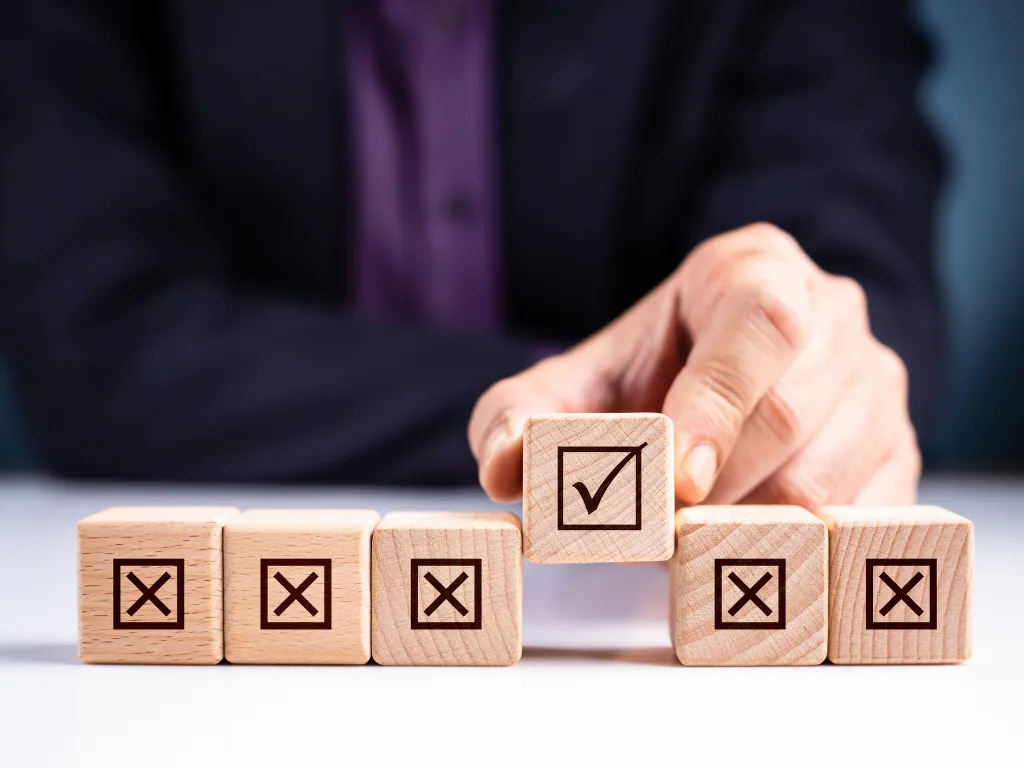 Businessperson selecting a wooden block with a check mark to represent choosing the best home value monitoring API