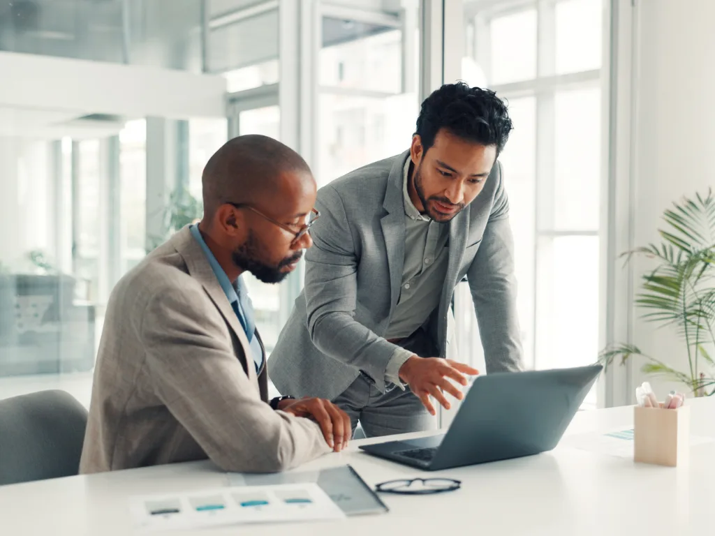Real estate investors reviewing property data and investment metrics on a laptop