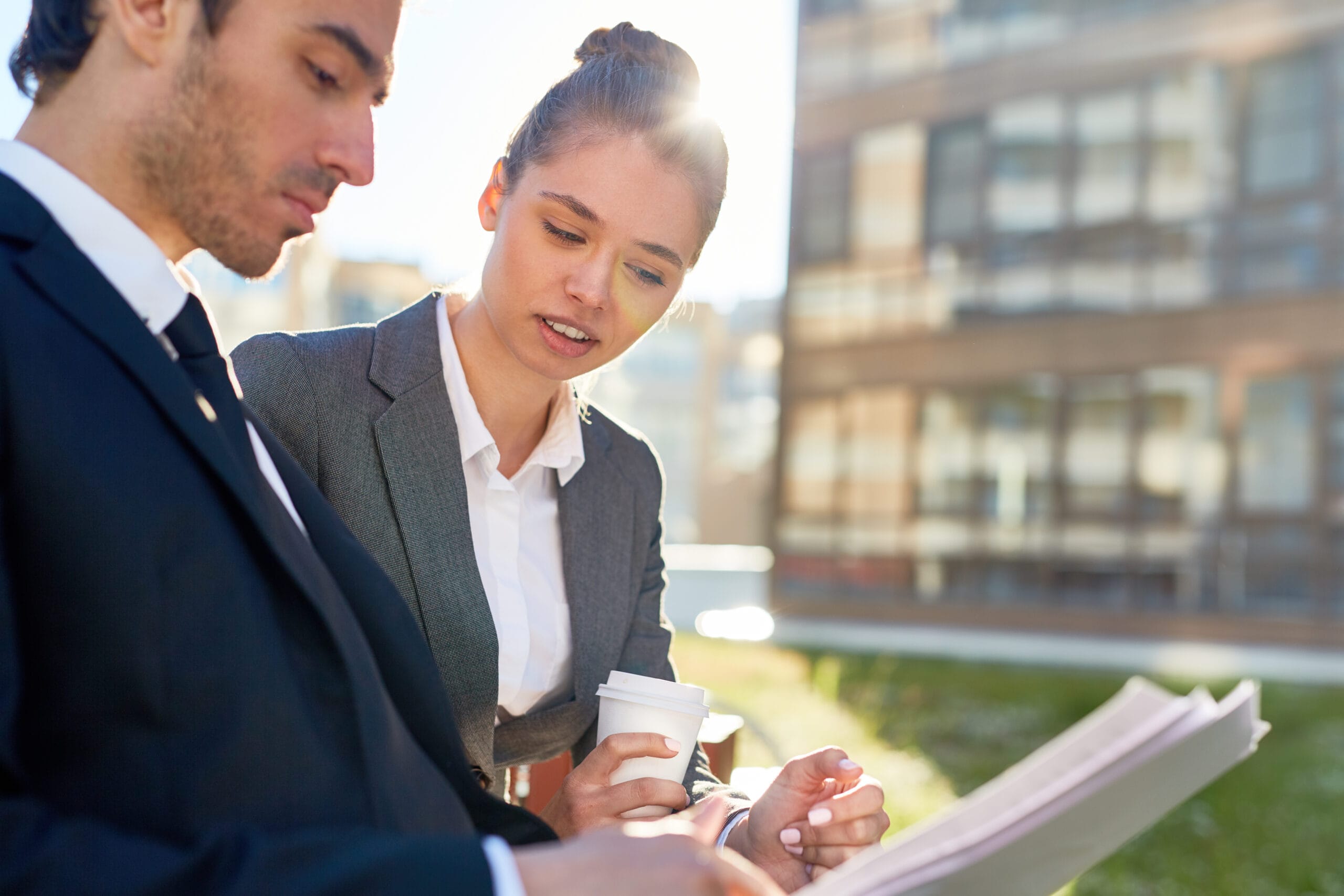 Two real estate professionals reviewing property documents outdoors in a business setting