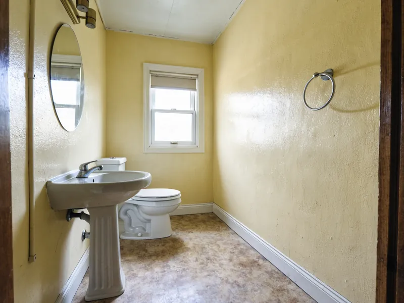 Second bathroom with a pedestal sink and worn walls